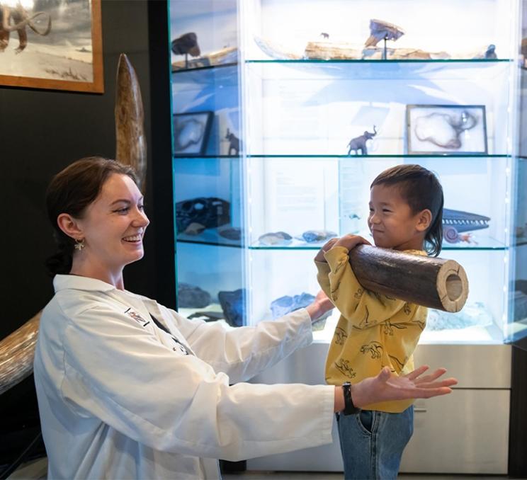 A guide has a child lift a wooly mammoth tusk at DinoLab Inc. in Victoria, BC