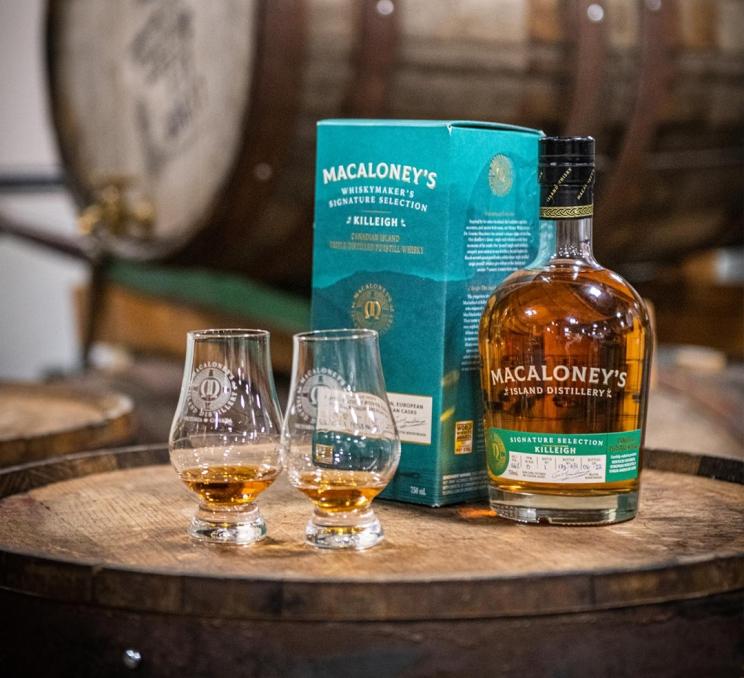 A display of a bottle of Island whiskey alongside two drams on top of a whiskey barrel at Macaloney's Island Distillery in Victoria, BC