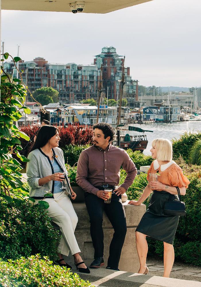 Three professionals enjoy drinks amidst a garden at the Inn at Laurel Point along the harbourfront in Victoria, BC