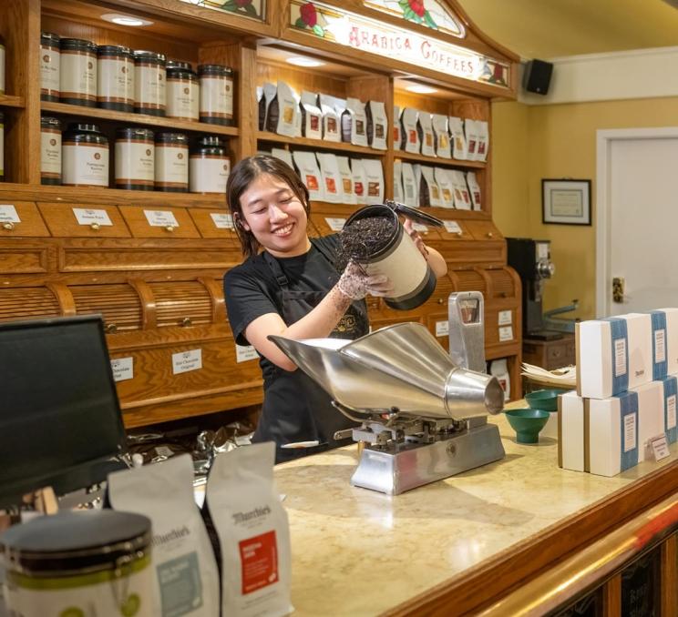 A woman pours loose leaf tea onto a measuring scale at Murchie's Tea & Coffee, a historic tea merchant in Victoria, BC