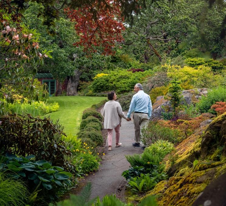 A couple walks hand-in-hand along a pathway through Abkhazi Garden in Victoria, BC