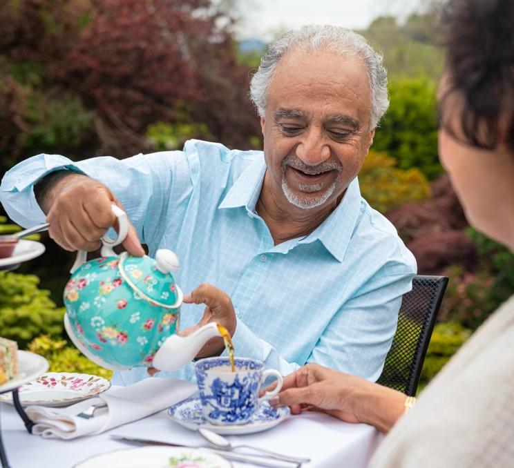 A man pours tea for his wife out of a turquoise tea pot while on the patio of Abkhazi Teahouse during Afternoon Tea service in Victoria, BC