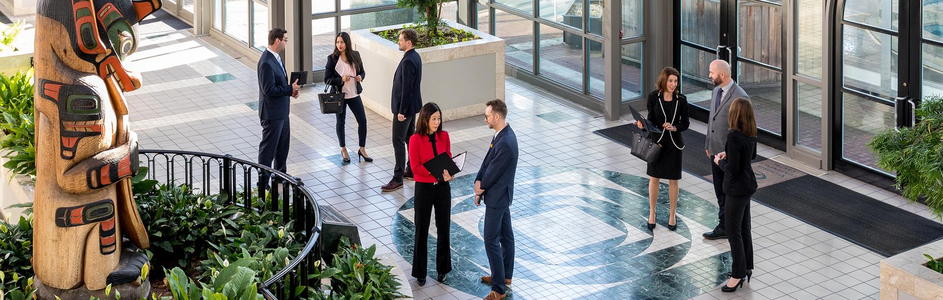 A group of workers from the Victoria Conference Centre meet at the Totem Atrium in Victoria, BC