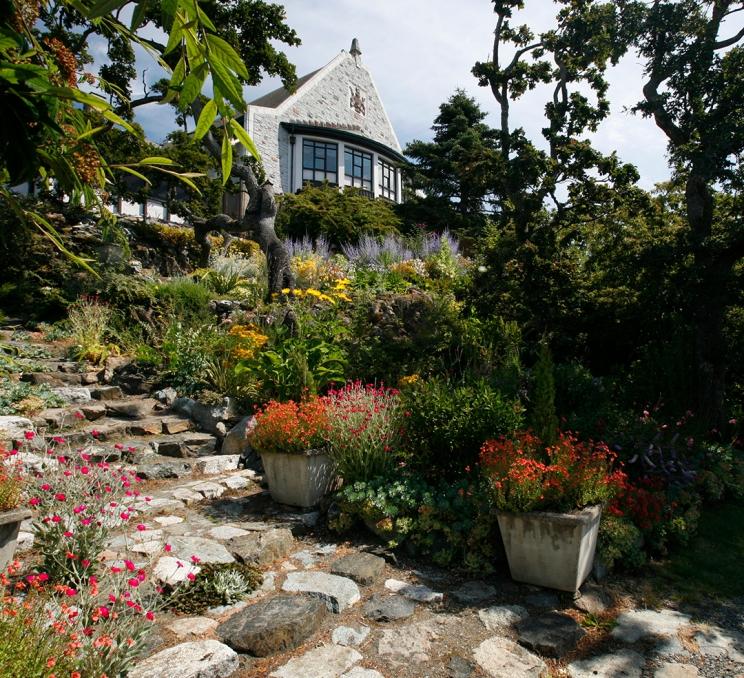 A view up a cobblestone pathway through the garden towards Government House, a historic site in Victoria, BC