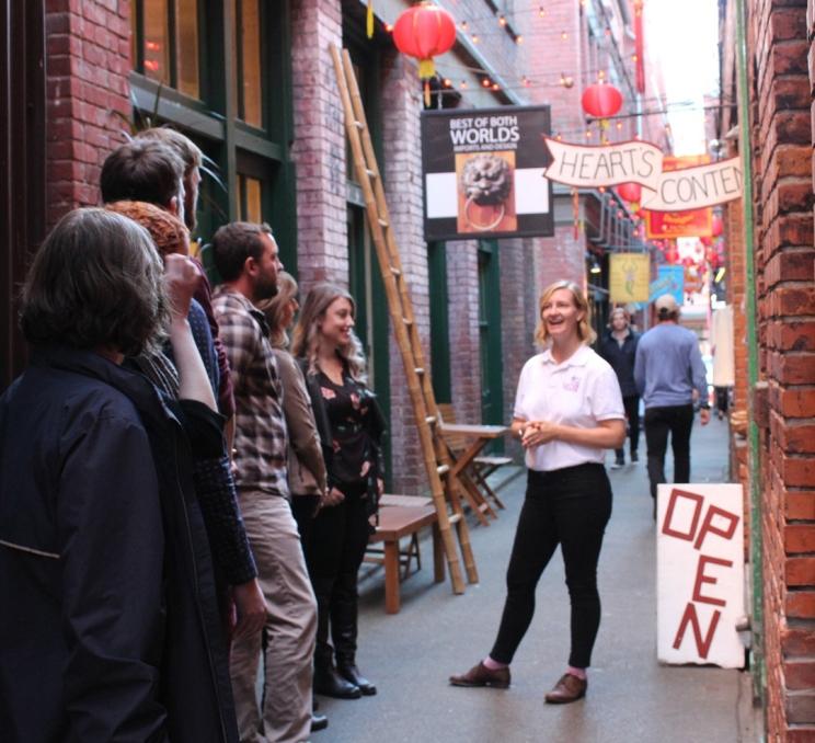 A group enjoys a guided food tour through Fan Tan Alley, the narrowest street in North America, in Victoria, BC