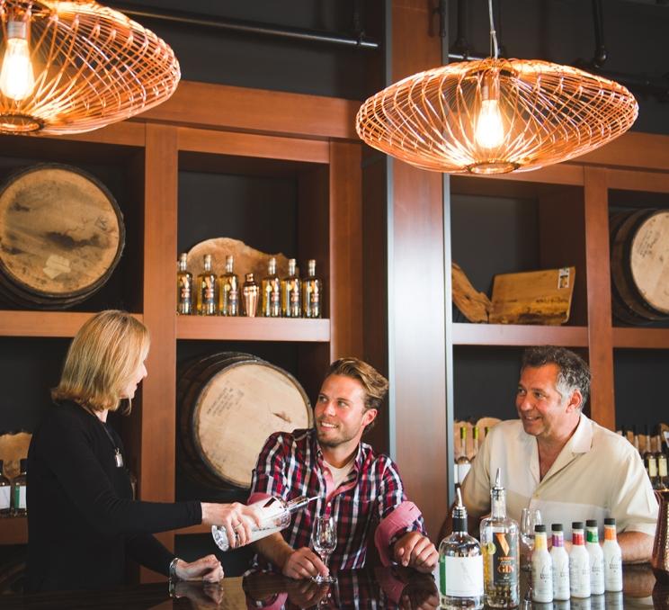 A woman provides a tasting at Victoria Distillers to two customers in Victoria, BC