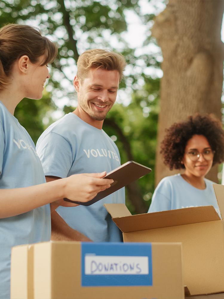 A group of volunteers in blue shirts load boxes together