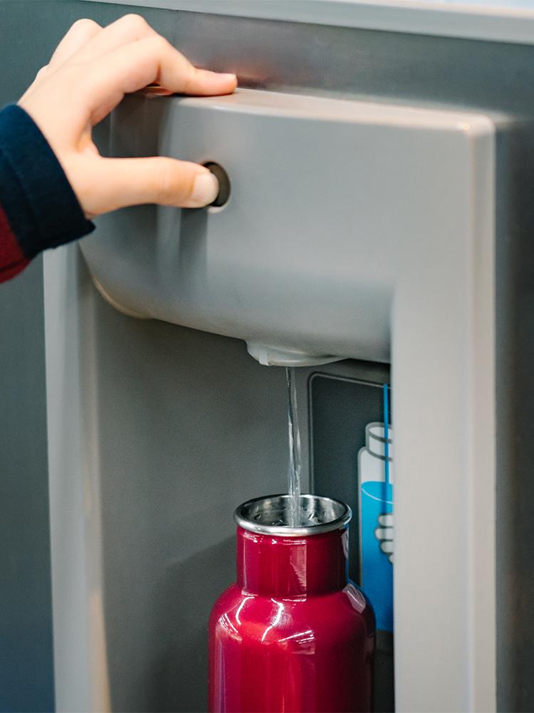 A red water bottle is refilled at a station
