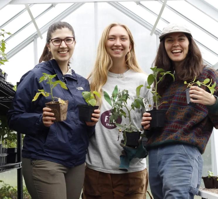 A group of people holding plants pose for a photo at FED Urban Farm in Victoria, BC