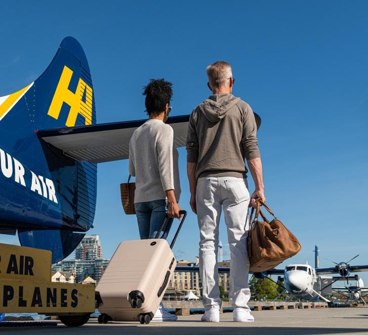 A couple stands with their luggage after disembarking a Harbour Air Seaplanes flight in Victoria, BC's Inner Harbour
