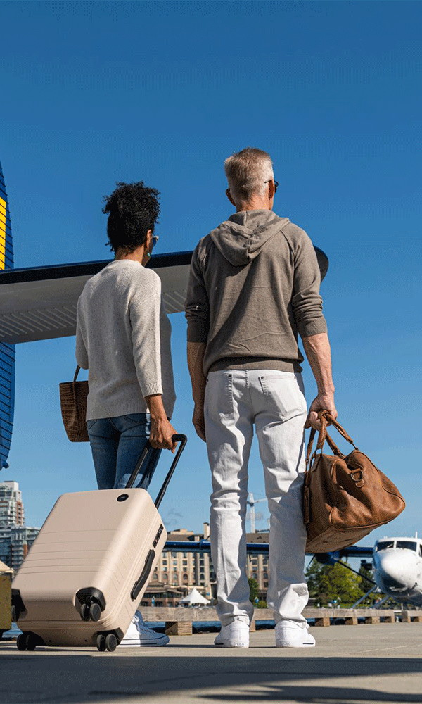 A couple arrives, bags in hand, at the seaplane terminal in Victoria BC's Inner Harbour