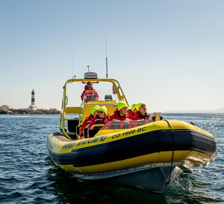 A zodiac whale watching tour leaves Race Rocks lighthouse on the Salish Sea off the coast of Victoria, BC