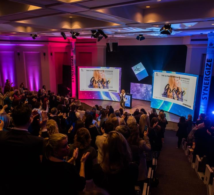 A lively audience fills the room, all eyes on the stage, creating a vibrant and engaging scene