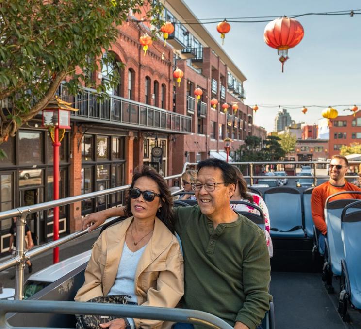 A couple rides a hop-on hop-off bus through Canada's oldest Chinatown in Victoria, BC