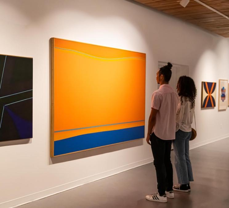 A couple examines an orange and blue art piece in the Art Gallery of Greater Victoria in Victoria, BC