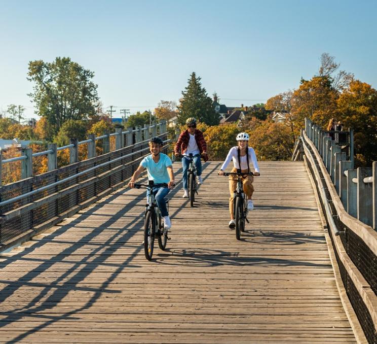 Three friends ride bikes along the Selkirk Trestle in Victoria, BC