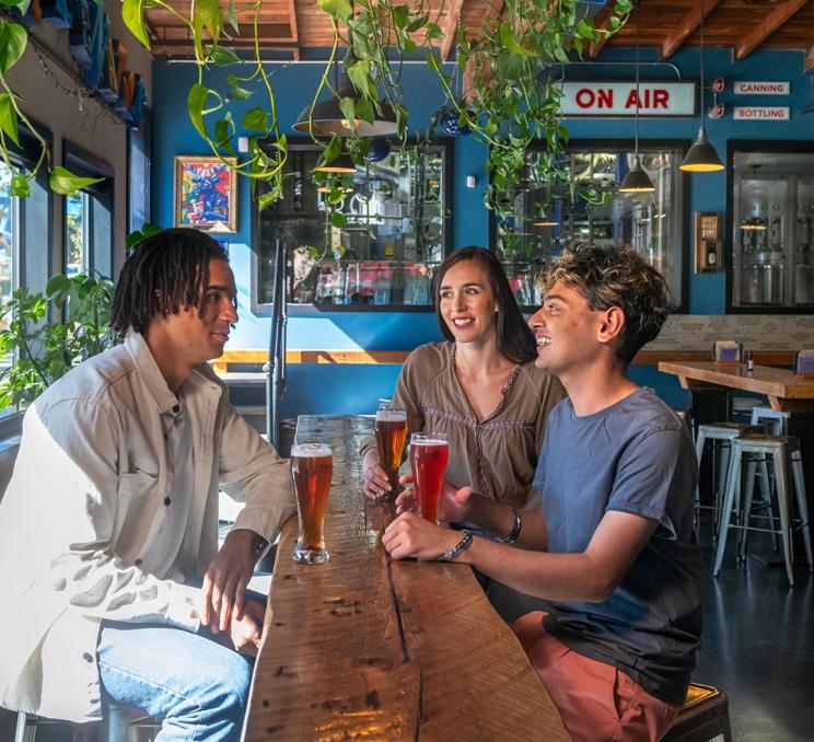 Three friends enjoy a round of beers in the west coast inspired taproom at Phillips Brewing & Malting in Victoria, BC